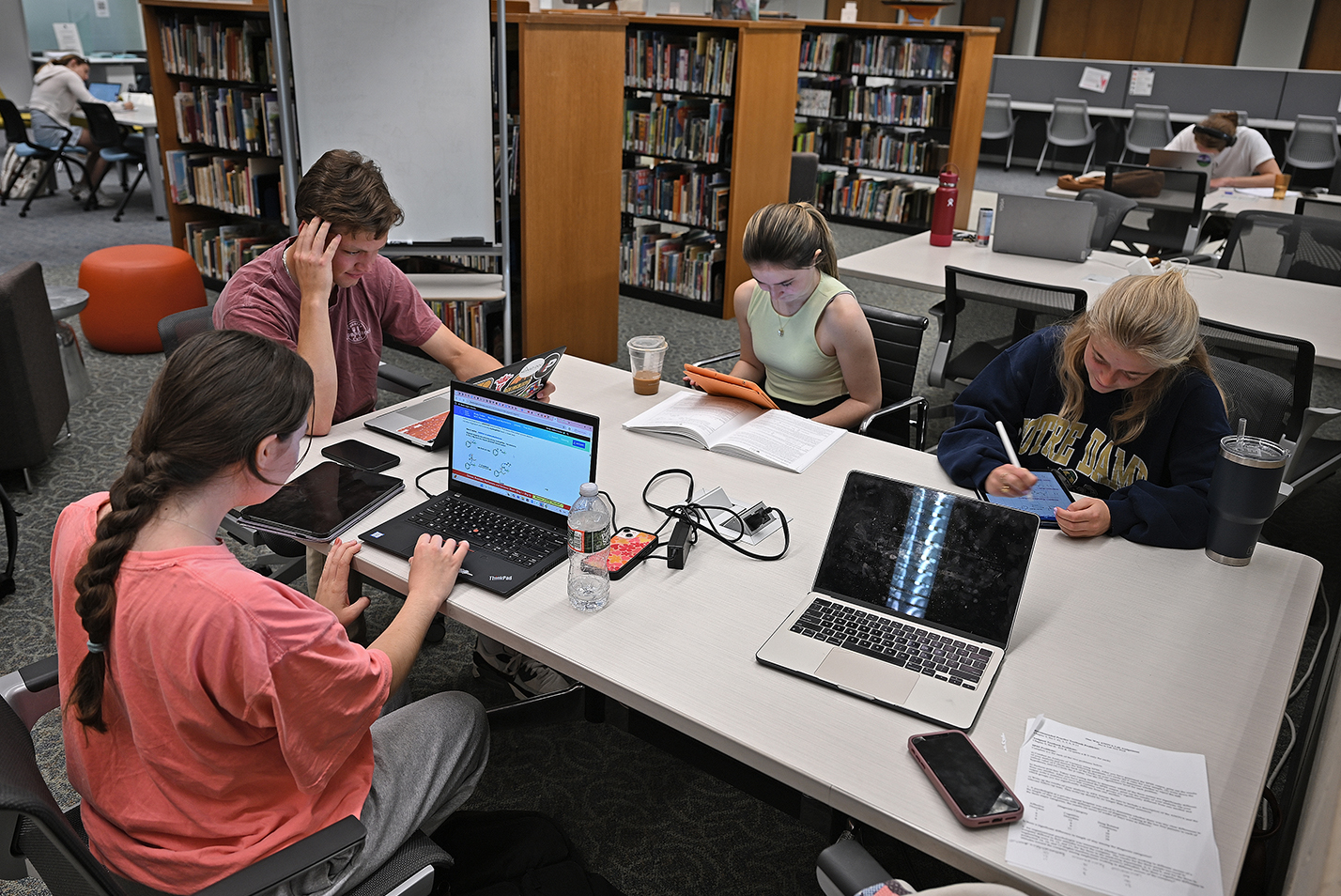 Students gather around a library table to study for final exams.