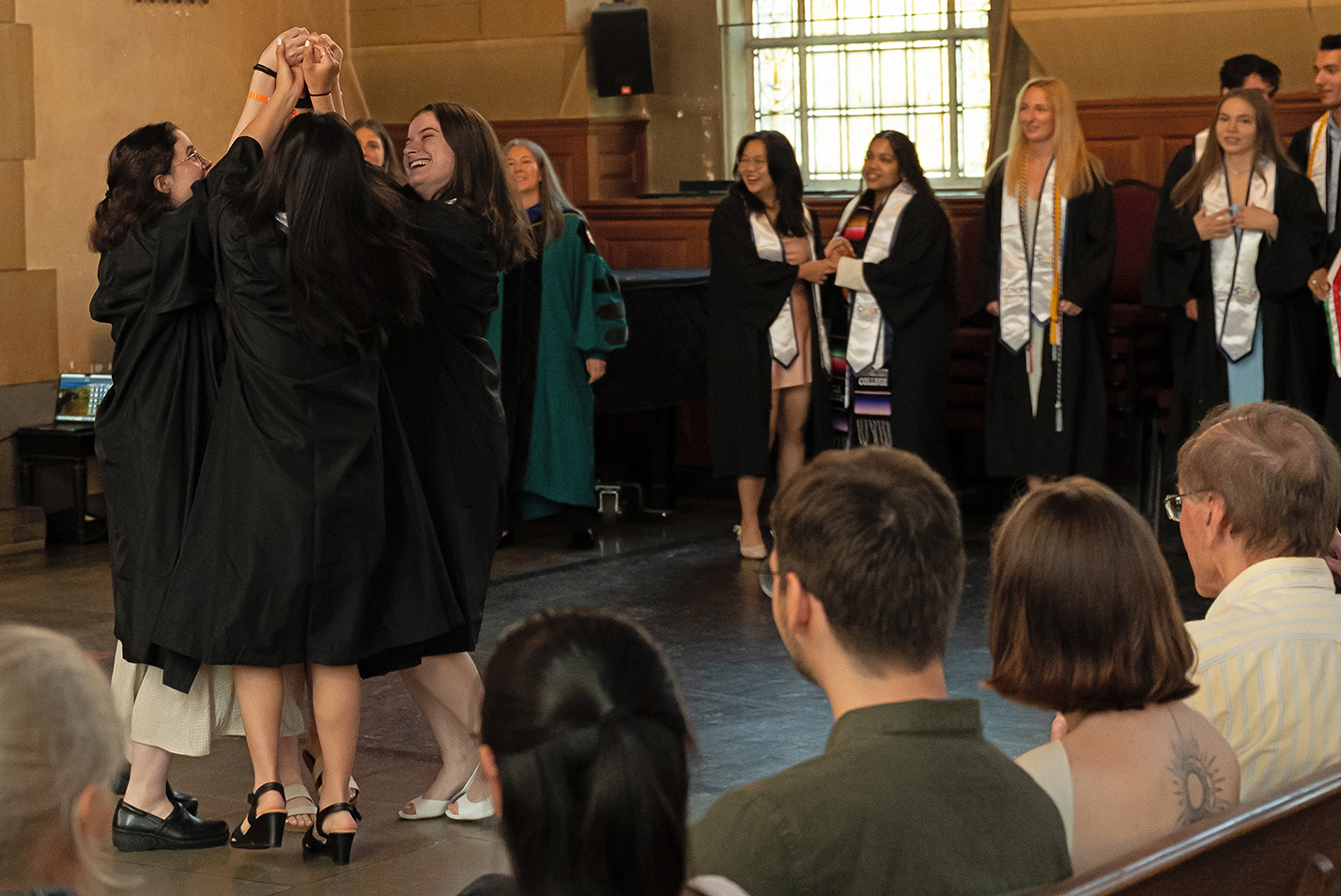 Students in graduation regalia perform a dance as part of a pre-commencement ceremony in the college chapel.