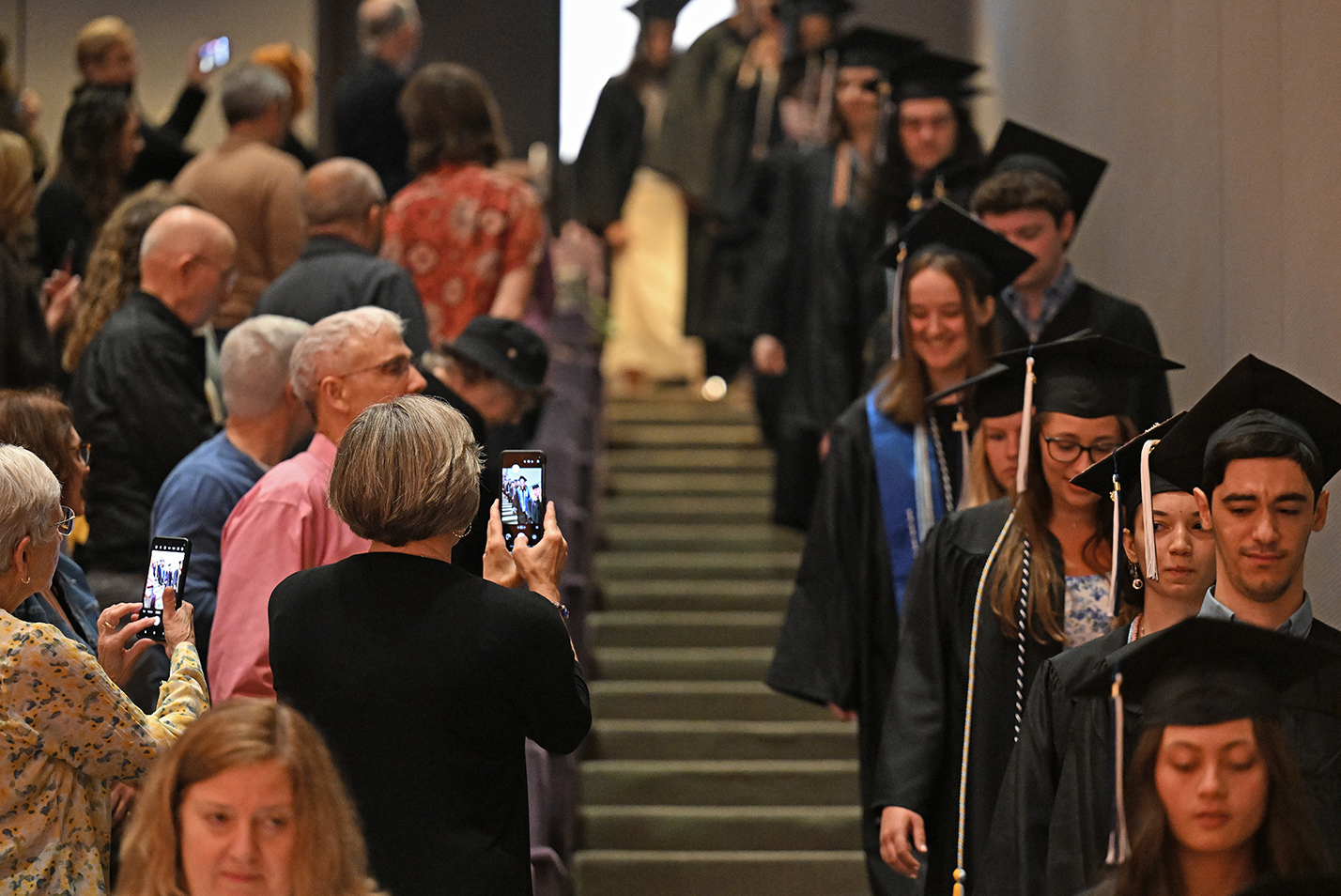 Parents take photos as their graduating seniors process into the room for an honor society induction ceremony.