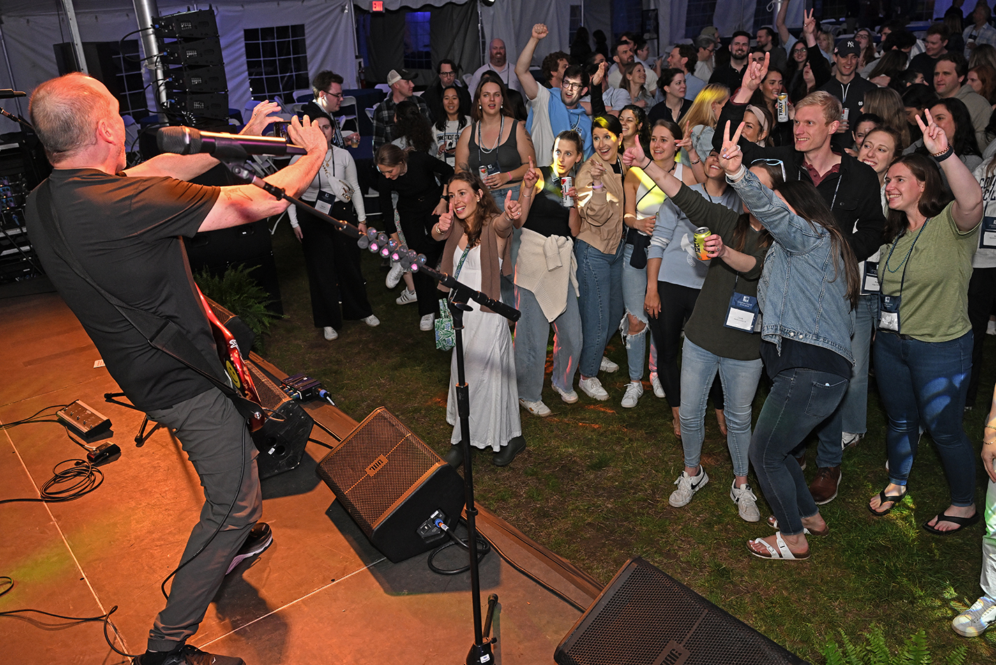 A member of a rock band on stage takes a photo of the audience during a concert.